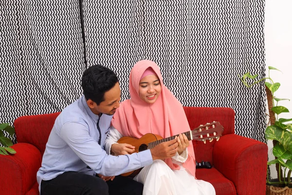 Pasangan Muslim Asia Duduk Sofa Merah Sambil Belajar Bermain Gitar — Stok Foto