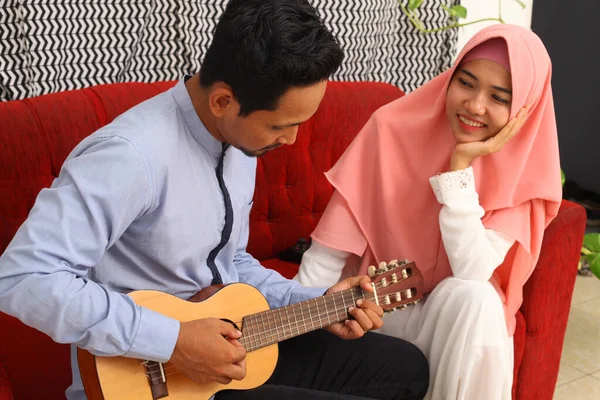Pasangan Muslim Asia Duduk Sofa Merah Saat Bermain Gitar — Stok Foto