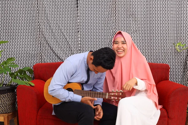 Pasangan Muslim Asia Duduk Sofa Merah Saat Bermain Gitar — Stok Foto