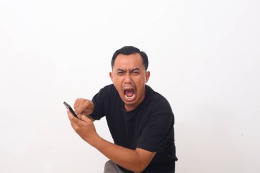 Çekici Asyalı genç adam telefonunu işaret ediyor, kötü haberler alıyor, beyazlar yerine kızgın davranışlar sergiliyor.