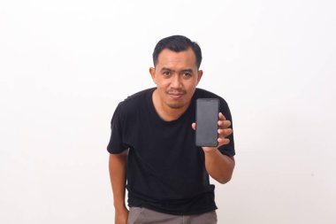 Siyah tişörtlü, sakallı, cep telefonuna gülümseyen, cihaz ya da mobil uygulama öneren Asyalı adamın portresi. Beyaz arka planda izole edilmiş kapalı stüdyo çekimi