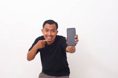 Siyah tişörtlü, cep telefonunu gösteren ve kameraya gülümseyen, mobil uygulama öneren tatmin olmuş Asyalı adamın portresi. Beyaz arka planda izole edilmiş. Cep telefonuna seçici odaklanma
