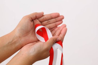 Bir insan eli, Endonezya bayrağının sembolü olarak kırmızı beyaz kurdele tutar. Beyaz arkaplanda izole