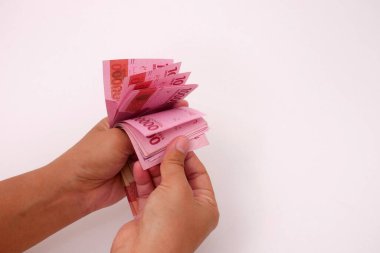 El ele tutuşan Endonezya parası, beyaz arka planlı 100.000 rupiah banknot.