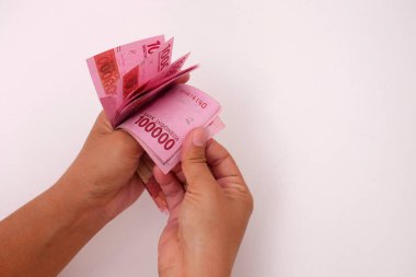 El ele tutuşan Endonezya parası, beyaz arka planlı 100.000 rupiah banknot.