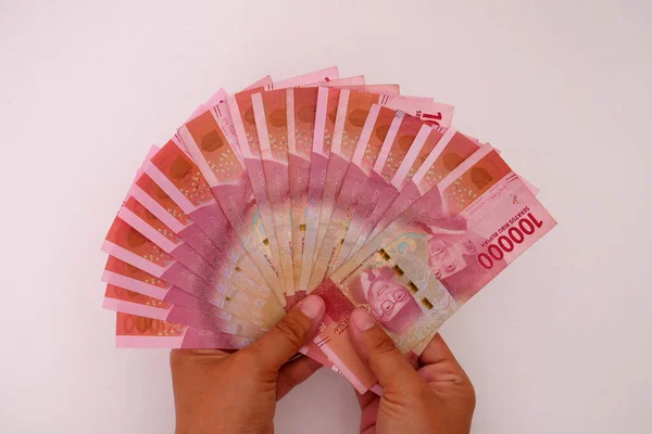 stock image Hand holding Indonesian currency, 100,000 rupiah banknotes with white background