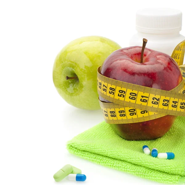 Red and green apples, vitamins and measuring tape. — Stock Photo, Image