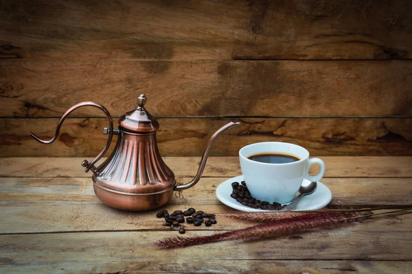 Винтажный чайник кофейных зерен и чашка кофе на деревянный стол — стоковое фото