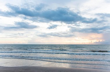 Deniz alacakaranlıkta, güneş batıyor, dalgalar soluk