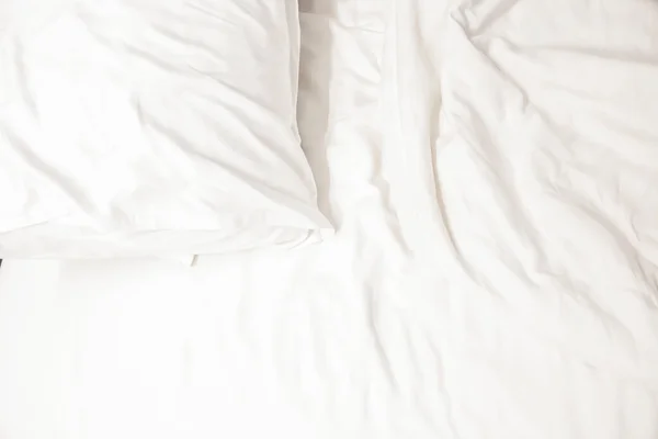 white pillow with messy messy blanket on bed in bedroom Close up of bedding sheets with copy space