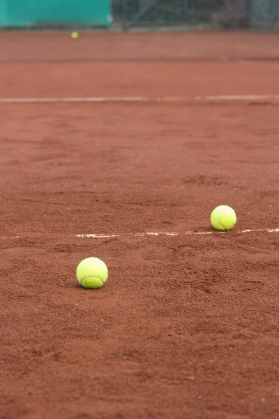 在红土场上的两个绿色网球球。 — 图库照片