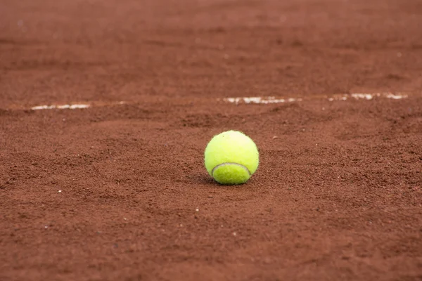 在红土场上的一个绿色网球球 — 图库照片