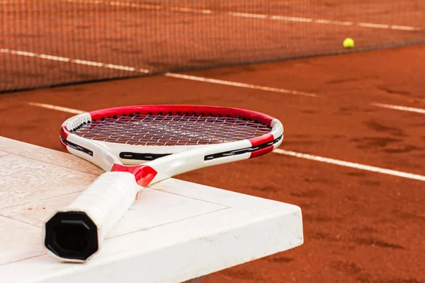 Raqueta de tenis en la mesa, cancha de barro, red de tenis y pelota — Foto de Stock