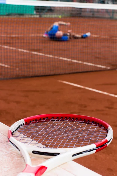 Tennisspiller tabte spillet og ruller på lerbanen - Stock-foto