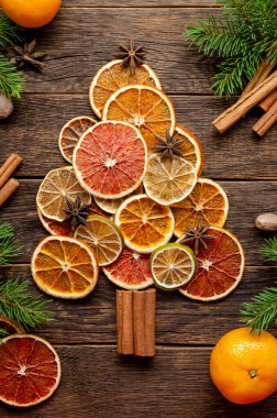 Kurutulmuş turunç ve tarçından yapılmış Noel ağacı, ahşap zemin üzerinde anason. Portakal, kireç, kırmızı