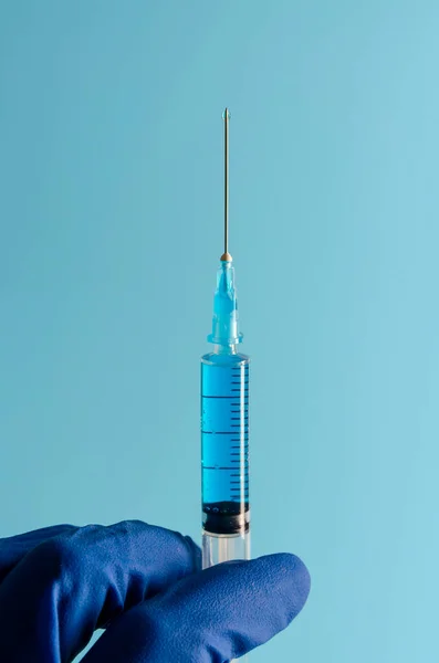 青の背景に手にコロナウイルスワクチンで注射 医学と薬 — ストック写真