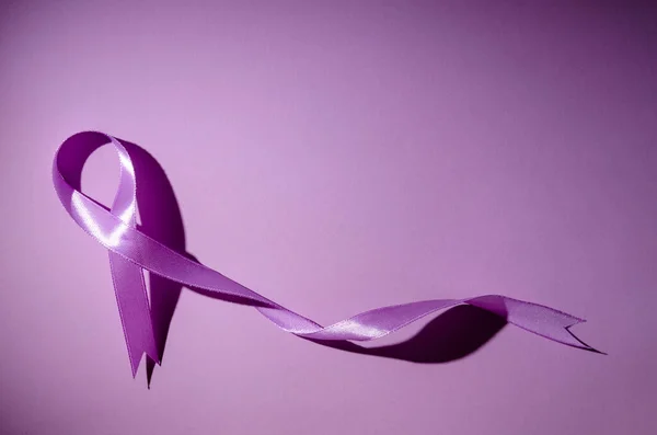 Purple awareness ribbon on a purple background. Copy space. World epilepsy awareness month.