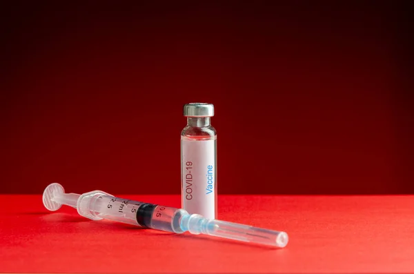 红色背景的医用注射器和COVID-19头孢病毒疫苗 — 图库照片