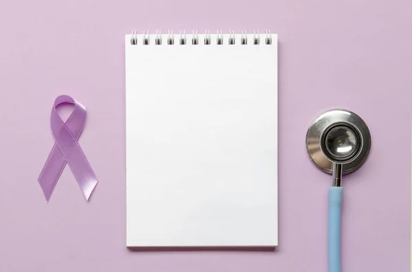 Notebook with purple awareness ribbon on a purple background. Copy space. World epilepsy awareness month.