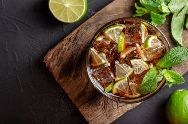 Küba libre, rom ve kola bardakta limon ve siyah arkaplanda nane.