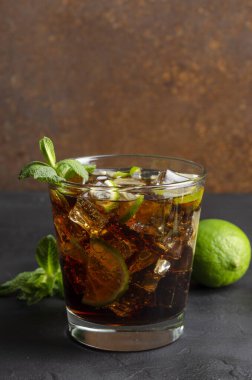 Küba libre, rom ve kola bardakta limon ve siyah arkaplanda nane.