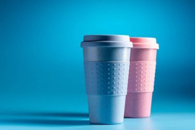 Açık mavi arka planda yeniden kullanılabilir kahve fincanı. Bambu kabı..