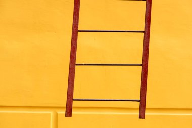 Boş sarı duvardaki eski merdivenler. Sarı soyut arkaplan.