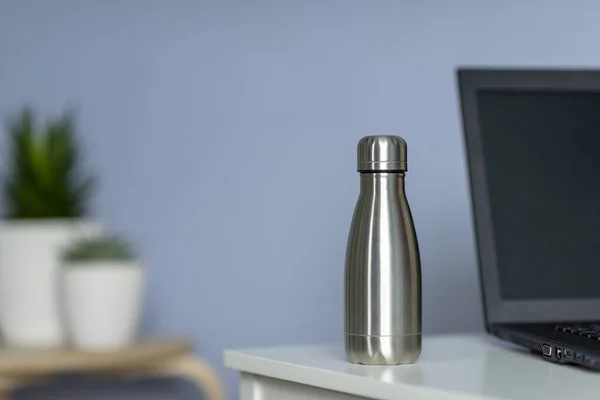 Die Frau hält zu Hause eine Wasserflasche aus Stahl auf dem Tisch. Keine Verschwendung. — Stockfoto