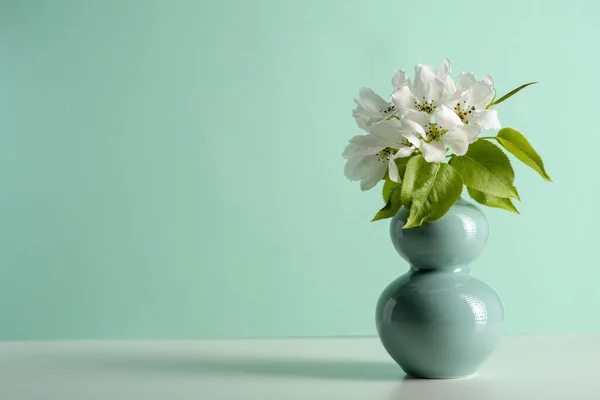 Fruit tree pear flowers in a turquoise jar on white table. Copy space — Stock Photo, Image