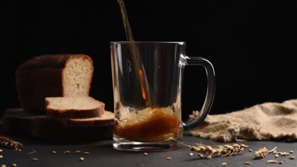 Een man giet kvass of donker bier in een glas op donkere achtergrond — Stockvideo