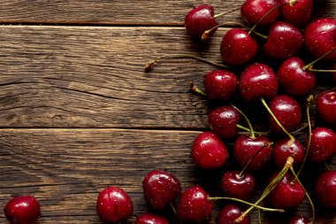 Tahta masadaki kirazlar ve kasede su damlaları.