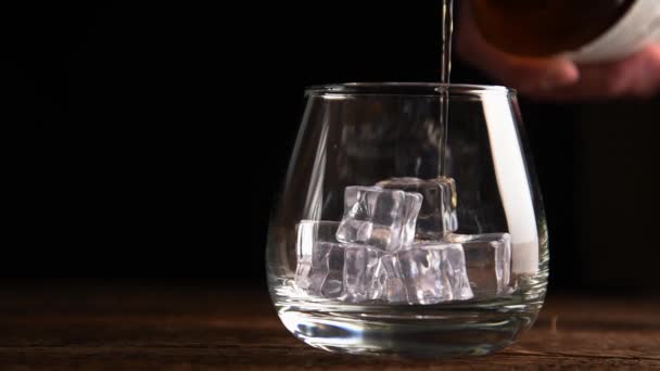 Şişeden buz küpleriyle bardağa viski dökülüyor.. — Stok video