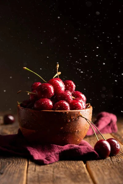 Cherries on wooden table with water drops on the bowl — Stock Photo, Image