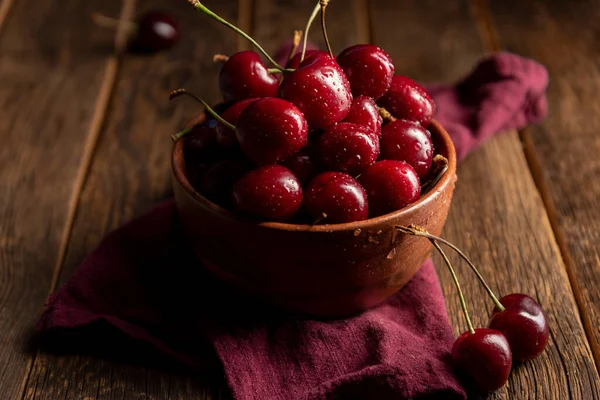 Cherries on wooden table with water drops on the bowl — Stock Photo, Image