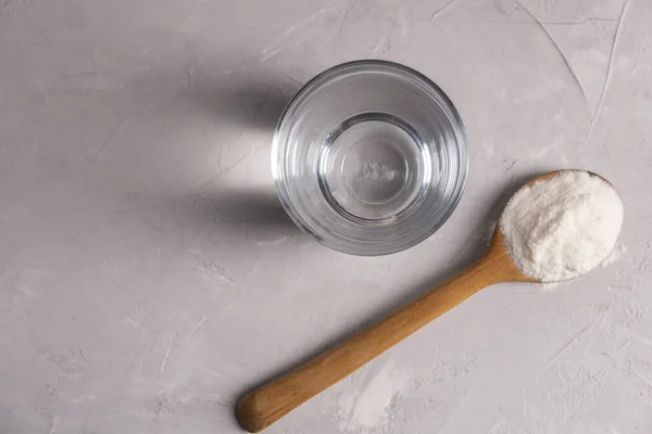 Polvo de colágeno con un vaso de agua sobre un fondo gris con espacio para copiar. — Foto de Stock