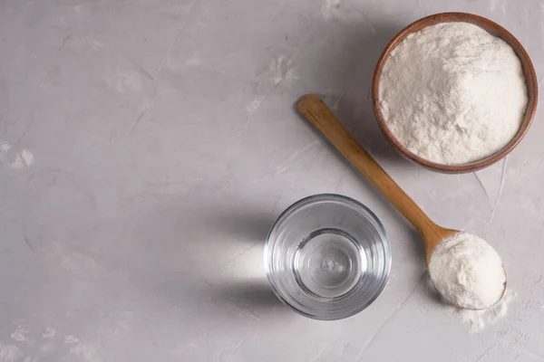 Polvo de colágeno con un vaso de agua sobre un fondo gris con espacio para copiar. — Foto de Stock