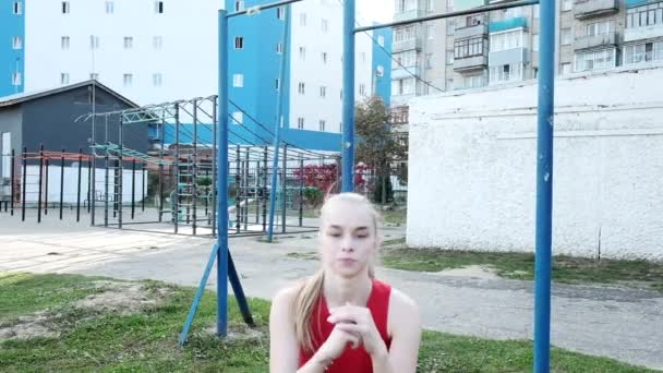 Passar ung blond bystig kvinna utbildning, gör knäböj och hoppar på idrottsplats — Stockvideo