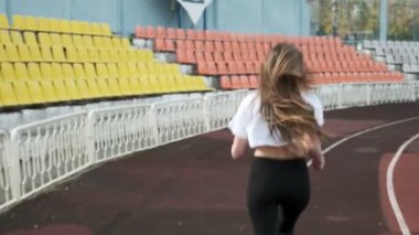 Sıska genç fitness güzel kadın koşucu spor giyim stadyumda koşuyor.