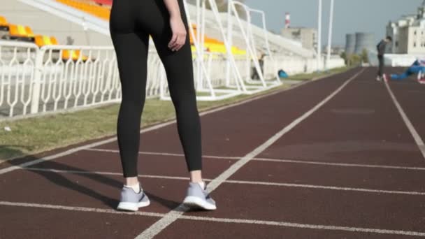 Két férfi előtt a stadionpályán futó, sportos, aktív ruhás nő — Stock videók