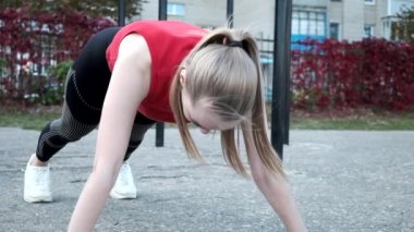 Spor giyimli at kuyruklu sarışın genç kadın spor sahasında çalışıyor.