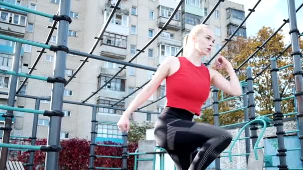 Молодая грудастая красивая женщина выполняет стоя кресты перекрестные упражнения в спортивной одежде — стоковое видео