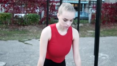 Sportif beyaz kadın spor sahasında şınav için tahta pozisyonunda duruyor.