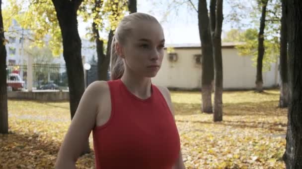 Nuori valkoihoinen povekas nainen venyttely hartiat, kädet ulkona, karkaaminen — kuvapankkivideo