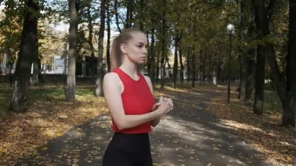 Jeune femme caucasienne aux gros seins étirant le cou et les bras à l'extérieur, fuyant — Video