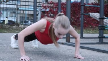 Spor giyimli at kuyruklu sarışın genç kadın spor sahasında çalışıyor.