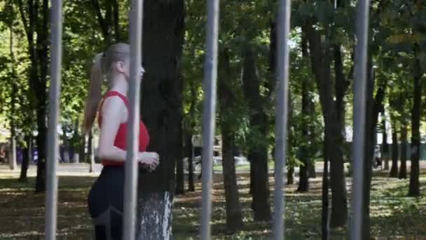 Caucásico chica de fitness corredor en ropa deportiva corriendo en el parque de otoño en el día soleado — Vídeos de Stock