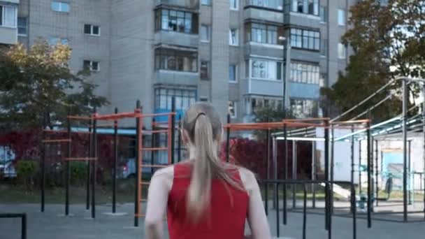 Follow-up shot of slim young fitness runner in sportswear running to sports ground — Stock Video