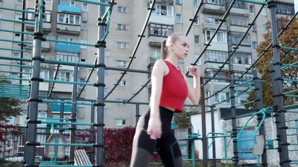 Молодая грудастая красивая женщина выполняет стоя кресты перекрестные упражнения в спортивной одежде — стоковое видео