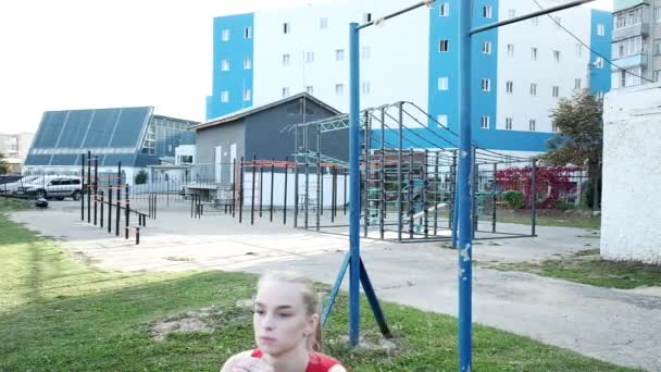 适合金发碧眼的年轻女子在运动场上训练、蹲伏和跳跃 — 图库视频影像