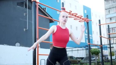 Genç, iri göğüslü, güzel bir kadın spor kıyafetlerinde çapraz egzersiz yapıyor.